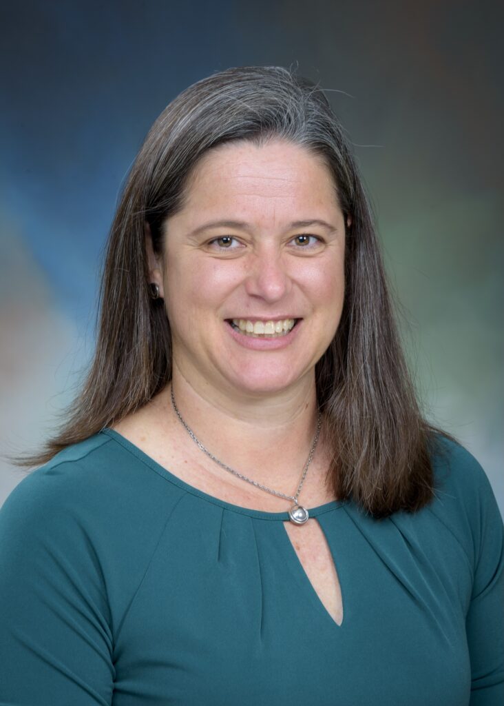 headshot of woman with long hair in teal blouse