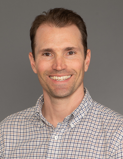 headshot of man with short hair, wearing a patterned shirt