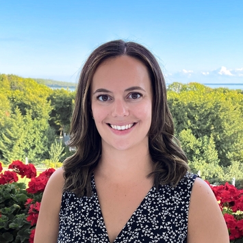 Woman in v-neck blouse standing in front of landscape